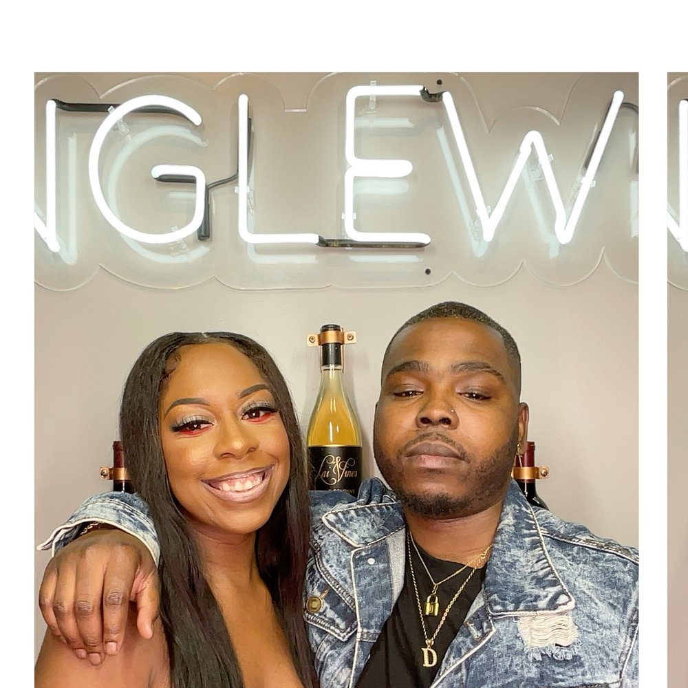 A couple posing under a neon sign at a wine night photo booth