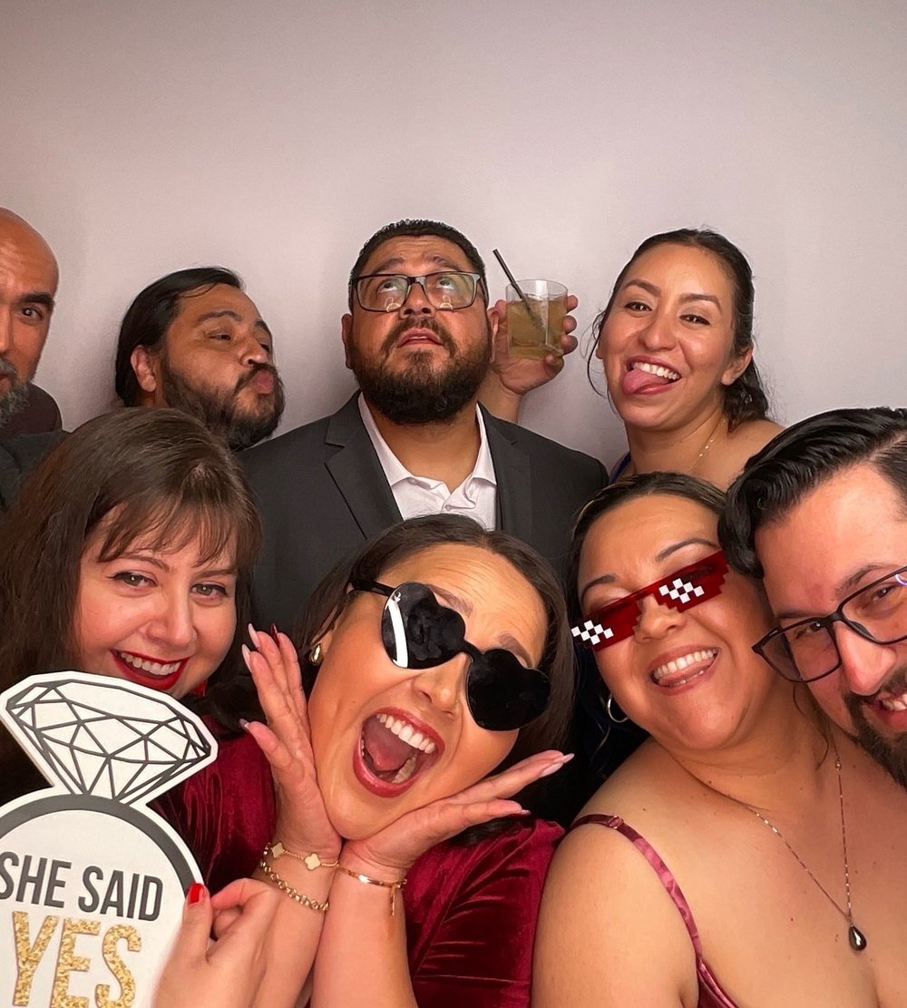 Wedding guests posing with sunglasses and a She Said Yes sign in the photo booth
