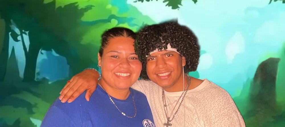 Two friends posing together at a night market photo booth