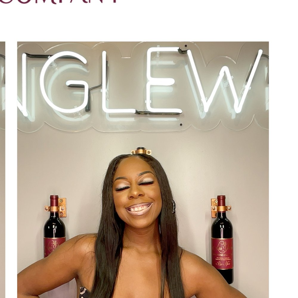 A guest smiling under a neon sign at a wine night photo booth