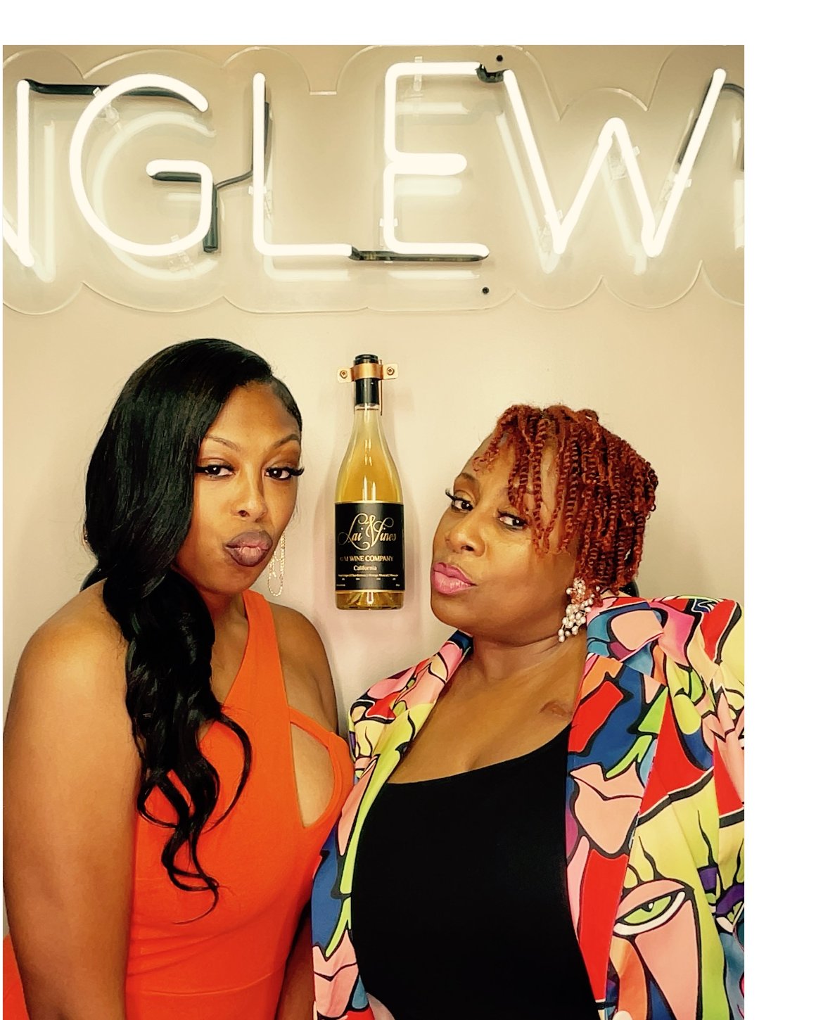 Two guests posing under a neon sign at a wine night photo booth